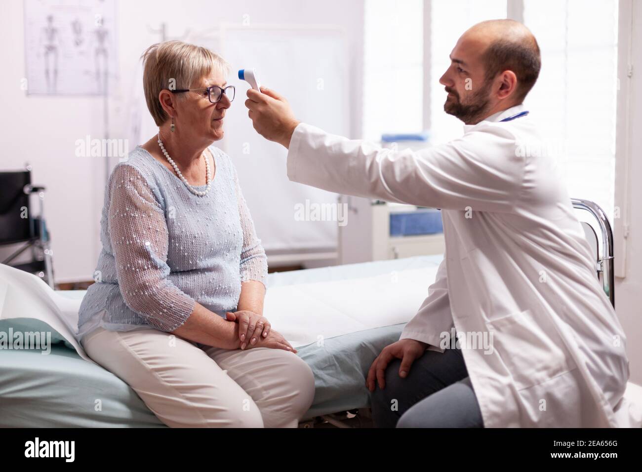 Personnel médical utilisant un thermomètre infrarouge pour prendre la température du corps de la vieille femme.consultation médicale pour les infections et les maladies pendant la pandémie mondiale, la grippe, l'outil, la maladie. Banque D'Images