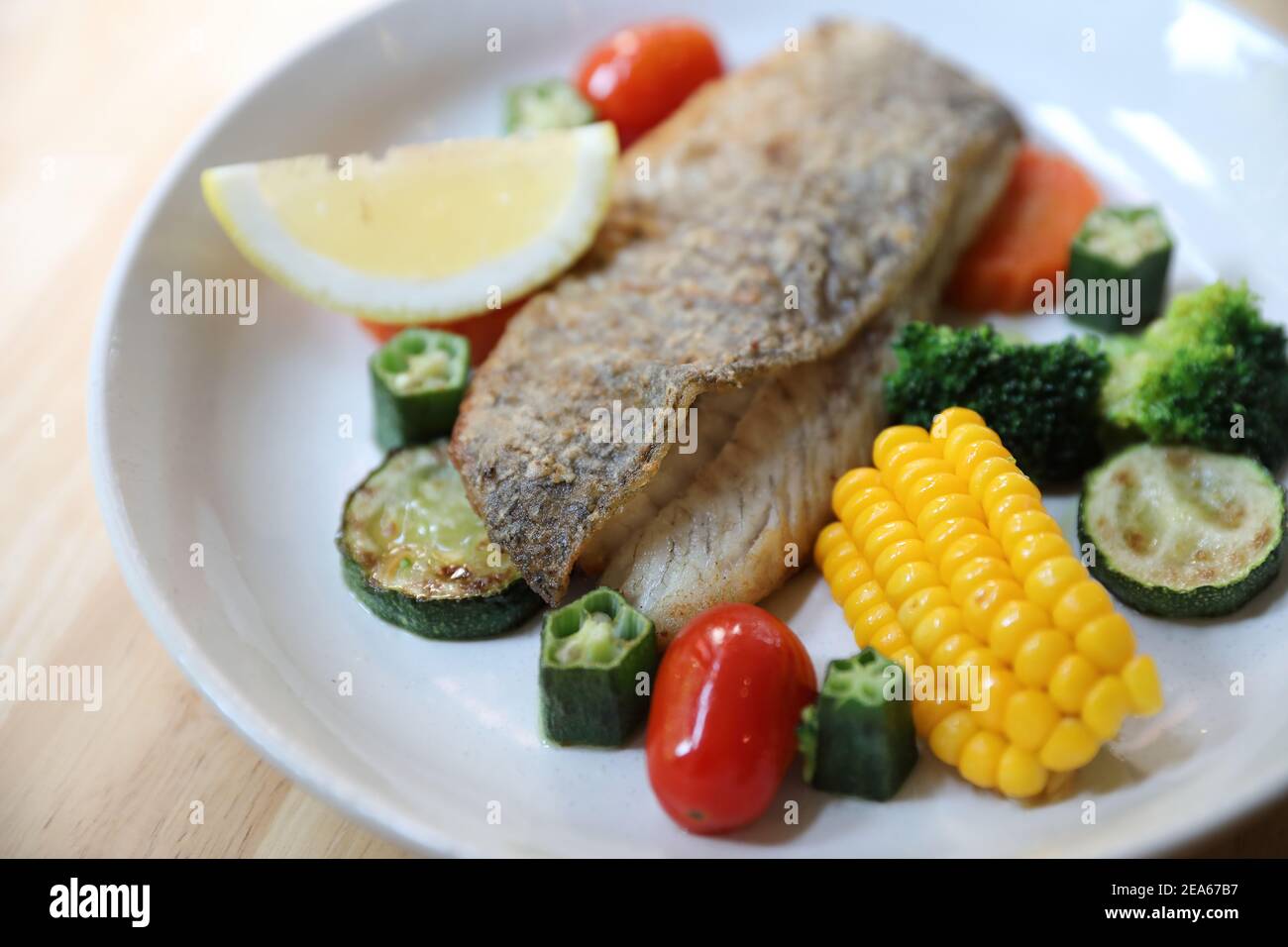 Filet de bar de mer, bar de mer cuit avec sauce au citron sur fond de bois Banque D'Images