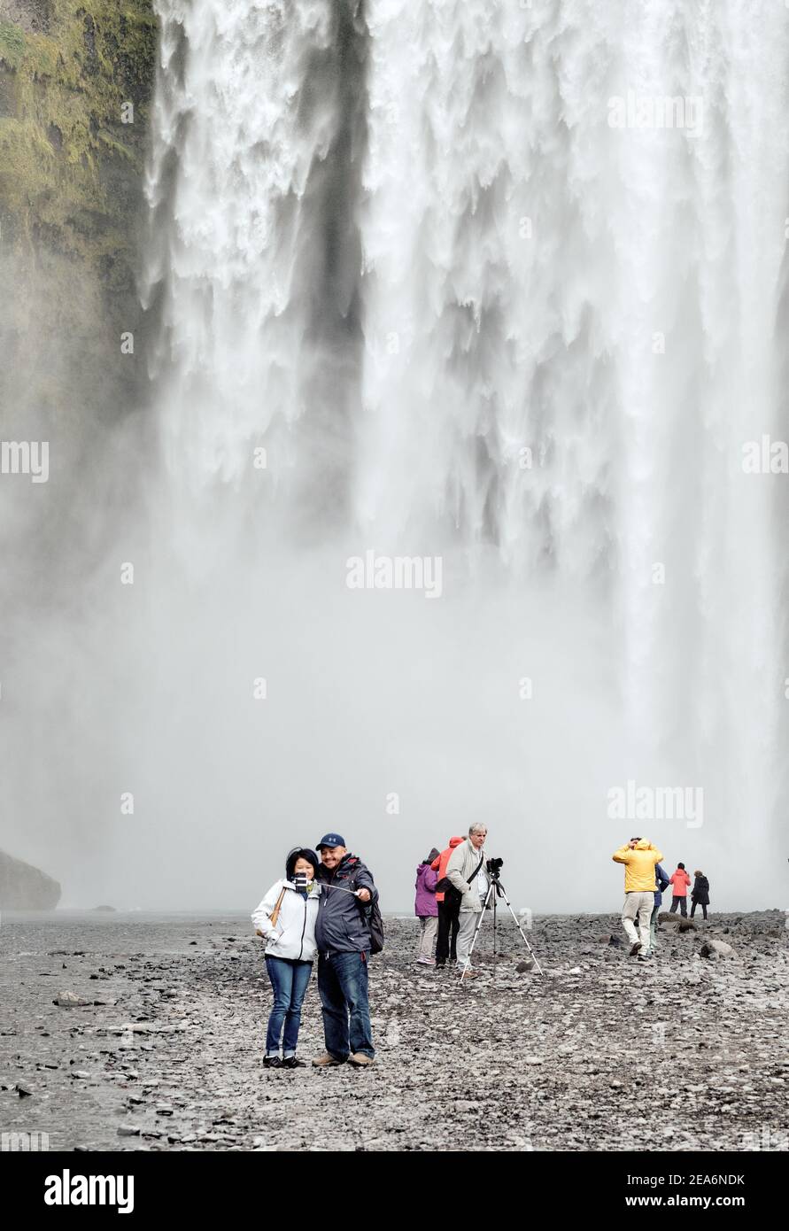Touristes appréciant et prenant des selfies à la destination touristique populaire de la cascade de Skogafoss dans le sud de l'Islande. Banque D'Images