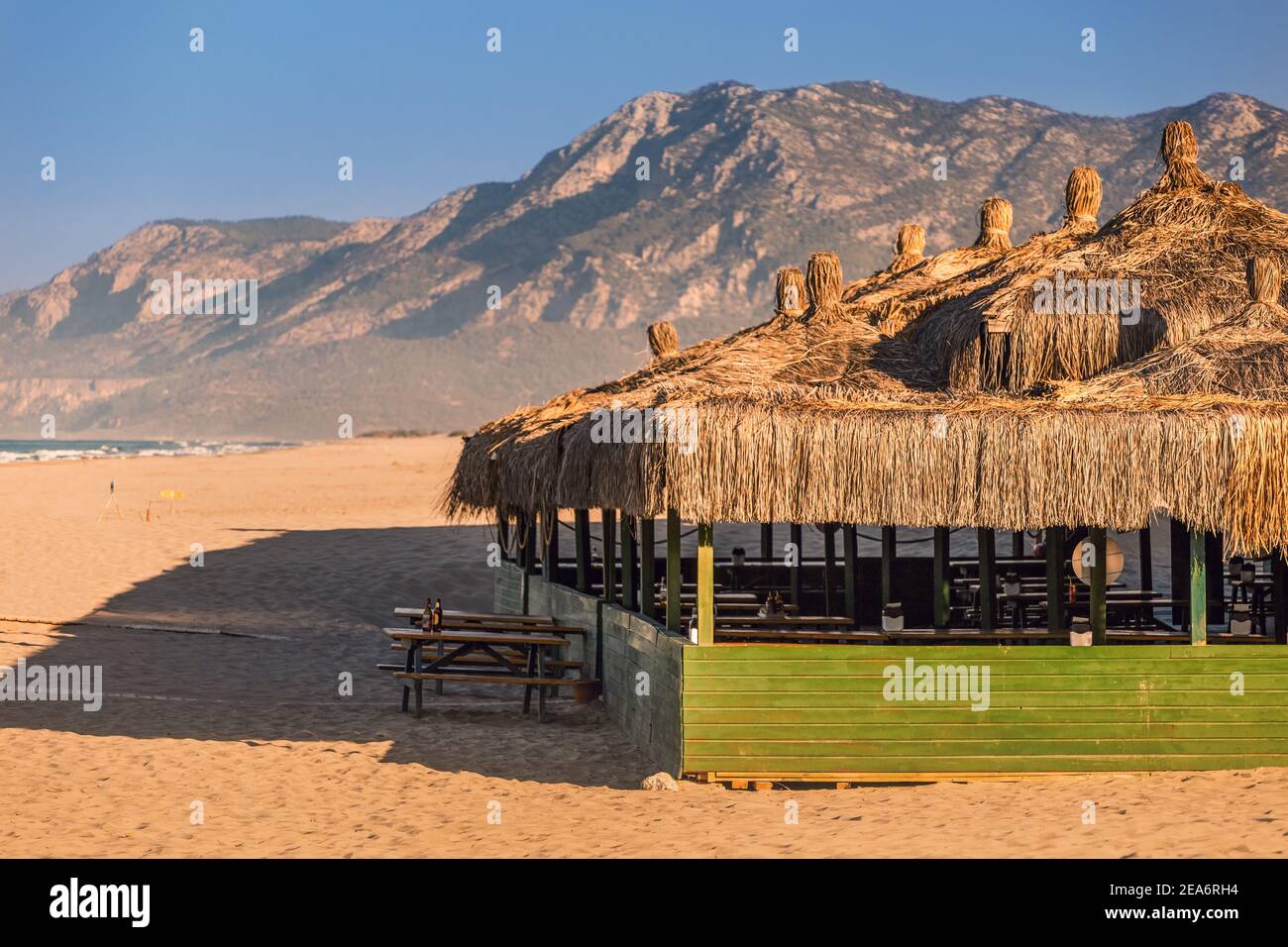 Une cafétéria vide et un restaurant sur le toit de chaume la plage et le bord de mer avec de hautes montagnes en arrière-plan Banque D'Images