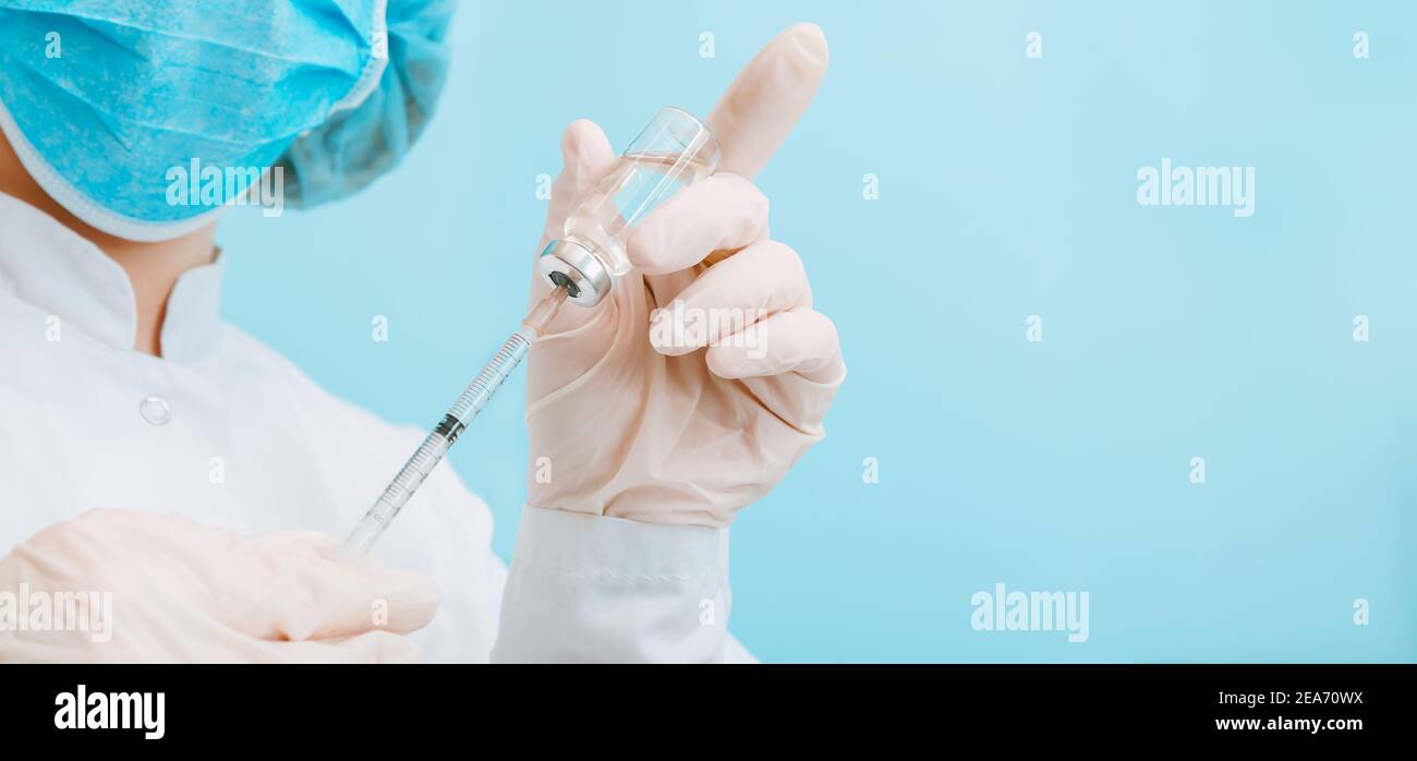 Médecin effectuant la vaccination dans un masque et des gants de protection. Covid 19 vaccin en flacon en verre flacon et seringue, médicament liquide dans la main du médecin Banque D'Images