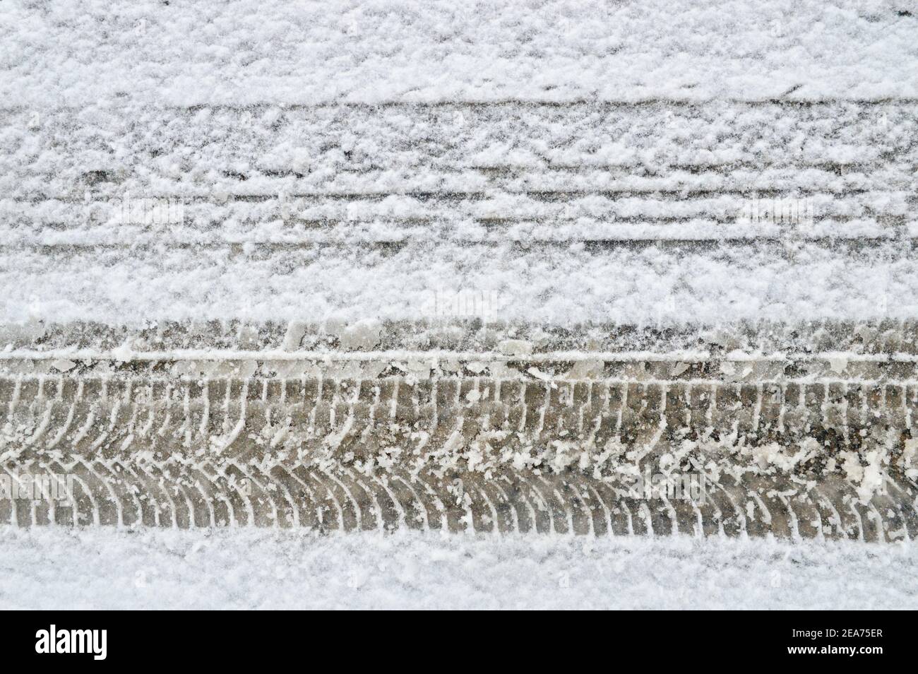 Différence sur une route enneigée entre un pneu standard et un pneu à neige avec chenilles Banque D'Images