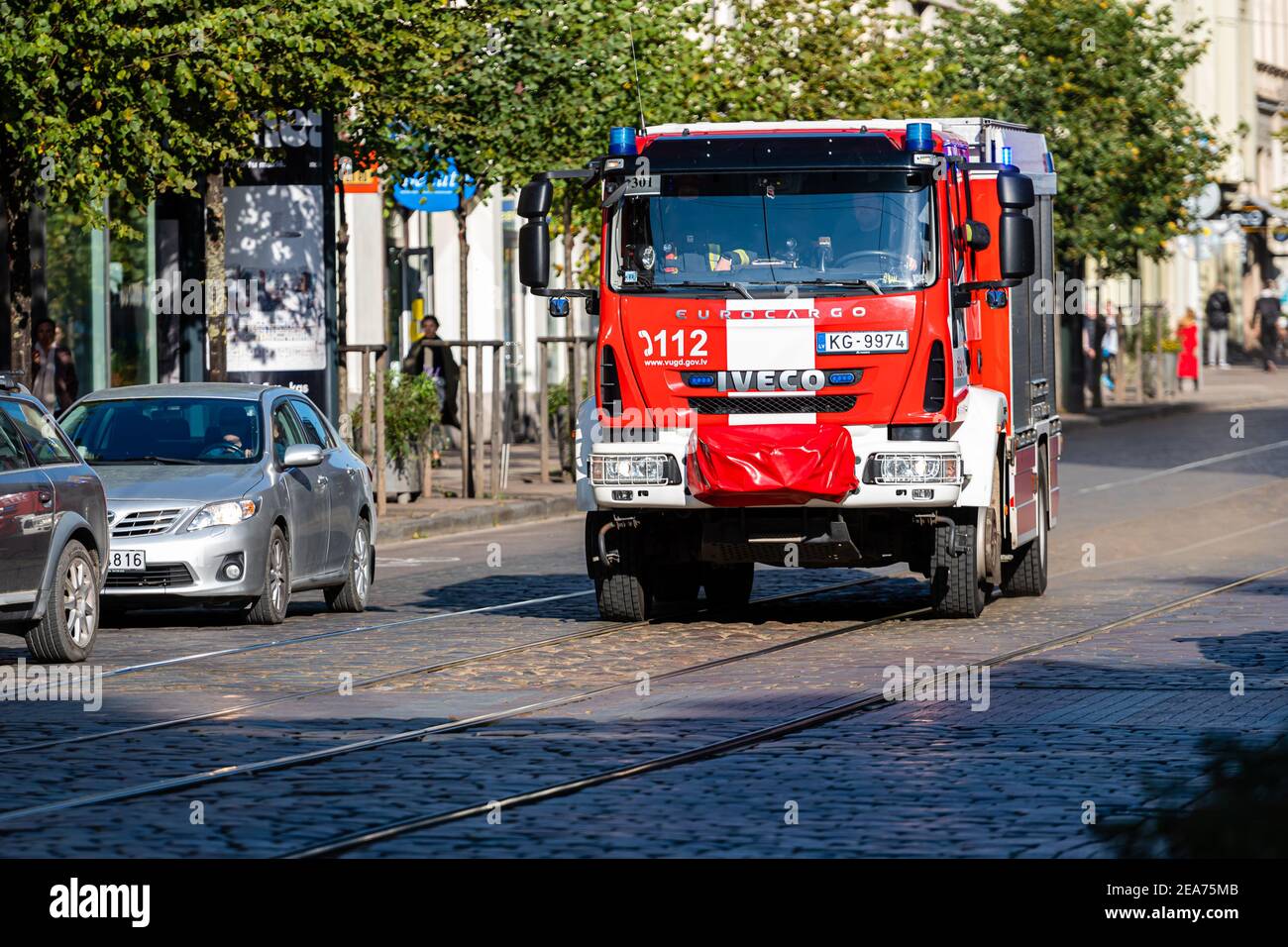 Riga, Lettonie - 7 octobre 2020:un camion d'incendie avec feux d'avertissement allumés va à un appel sur une rue pavée dans le centre-ville Banque D'Images