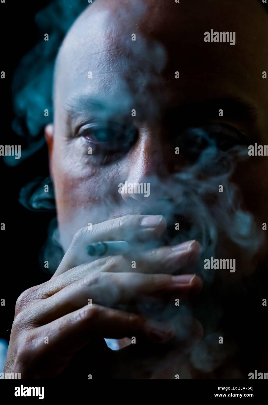 Homme fumant une cigarette qui dégage de la fumée blanche. Banque D'Images