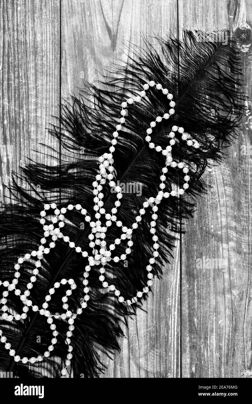 Image monochrome d'une chaîne de perles et de plumes noires surface en bois Banque D'Images