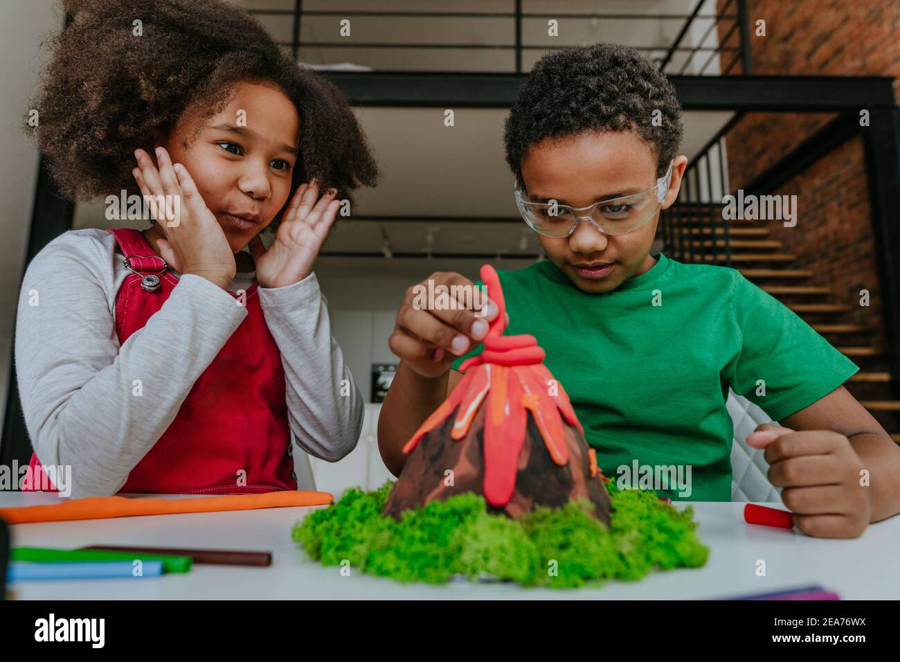 Sœur et frère ayant le plaisir de faire le bricolage volcan modèle des enfants jouent l'argile pour le projet d'école. Concept d'éducation à domicile. Banque D'Images