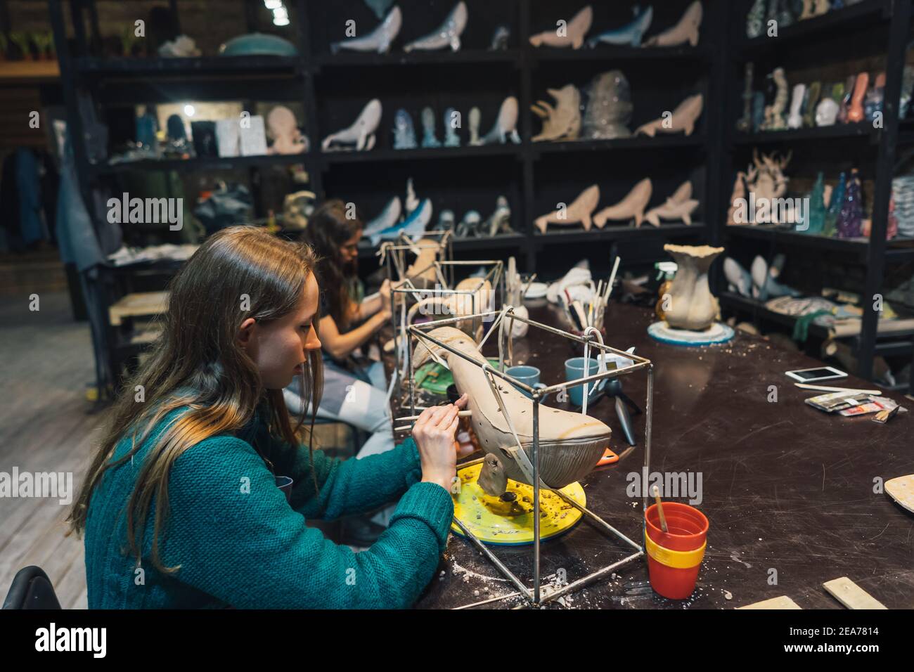 Les gens travaillent soigneusement sur les baleines en argile dans l'atelier Banque D'Images