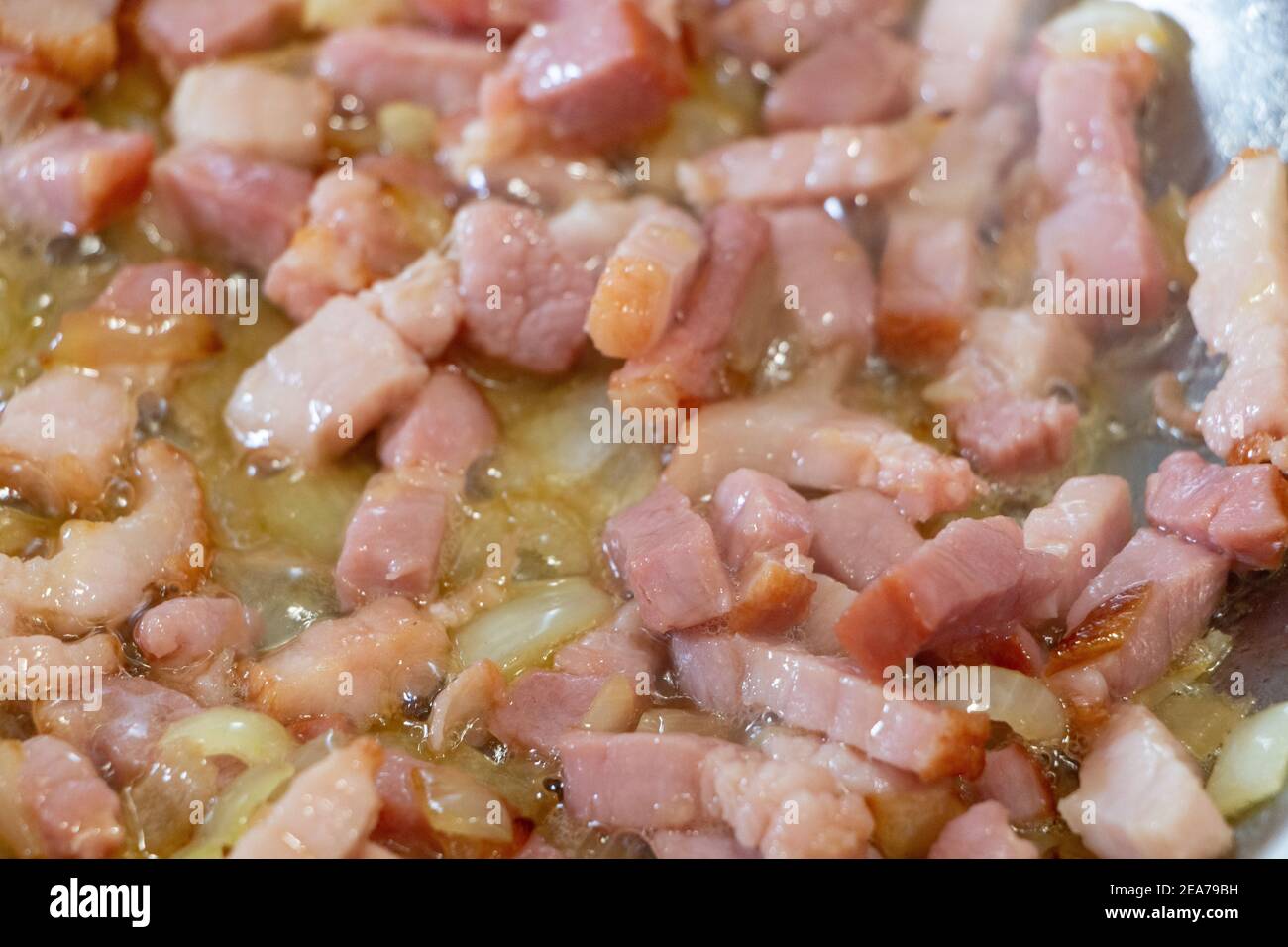 Morceaux d'oignon et cubes de bacon frits dans une poêle Banque D'Images