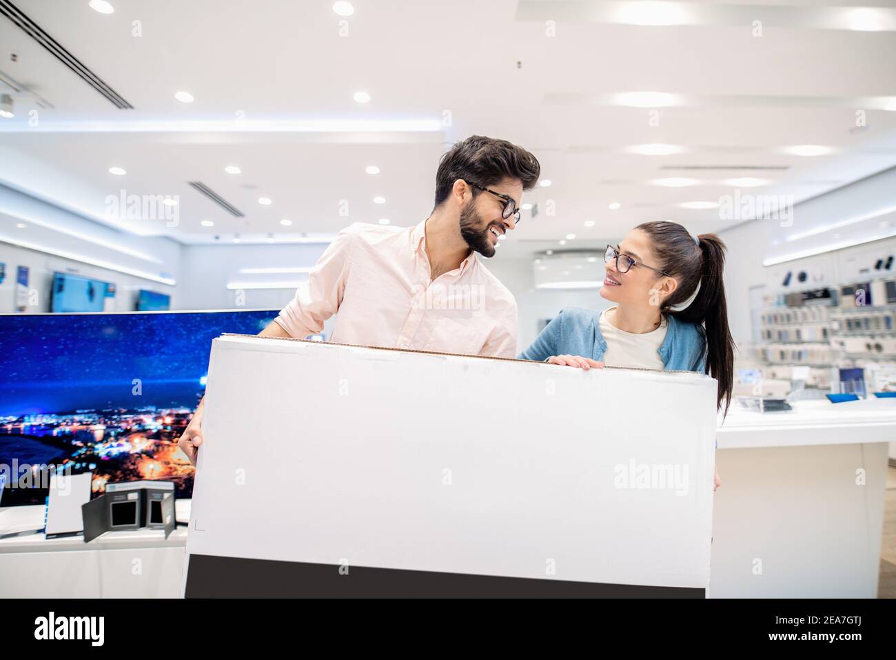 Un couple satisfait qui achète un nouveau téléviseur pour sa maison. Intérieur du magasin du technicien. Banque D'Images