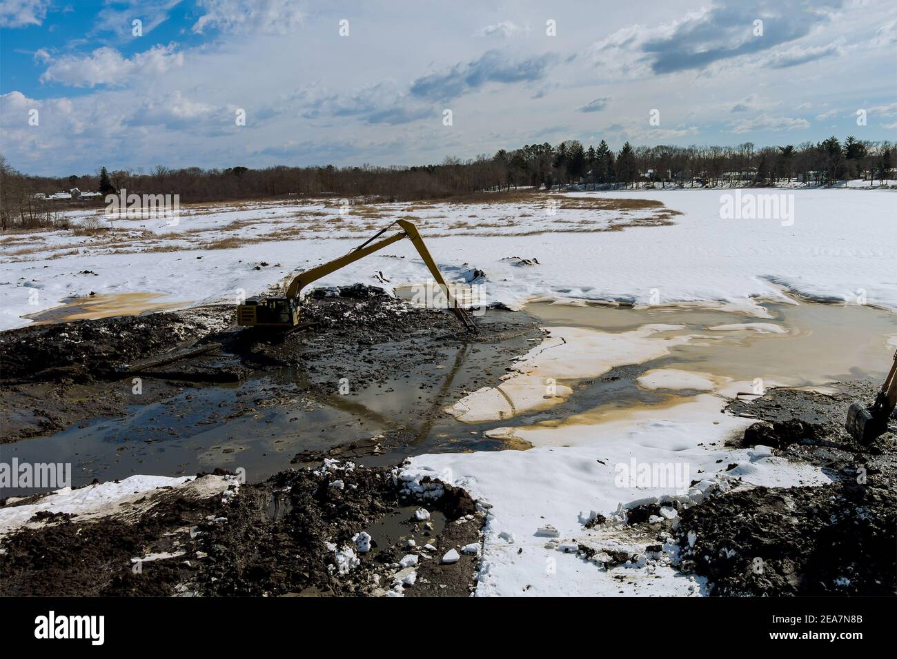 Une pelle hydraulique spécialisée nettoie les sédiments lacustres du fond du lac en hiver Banque D'Images