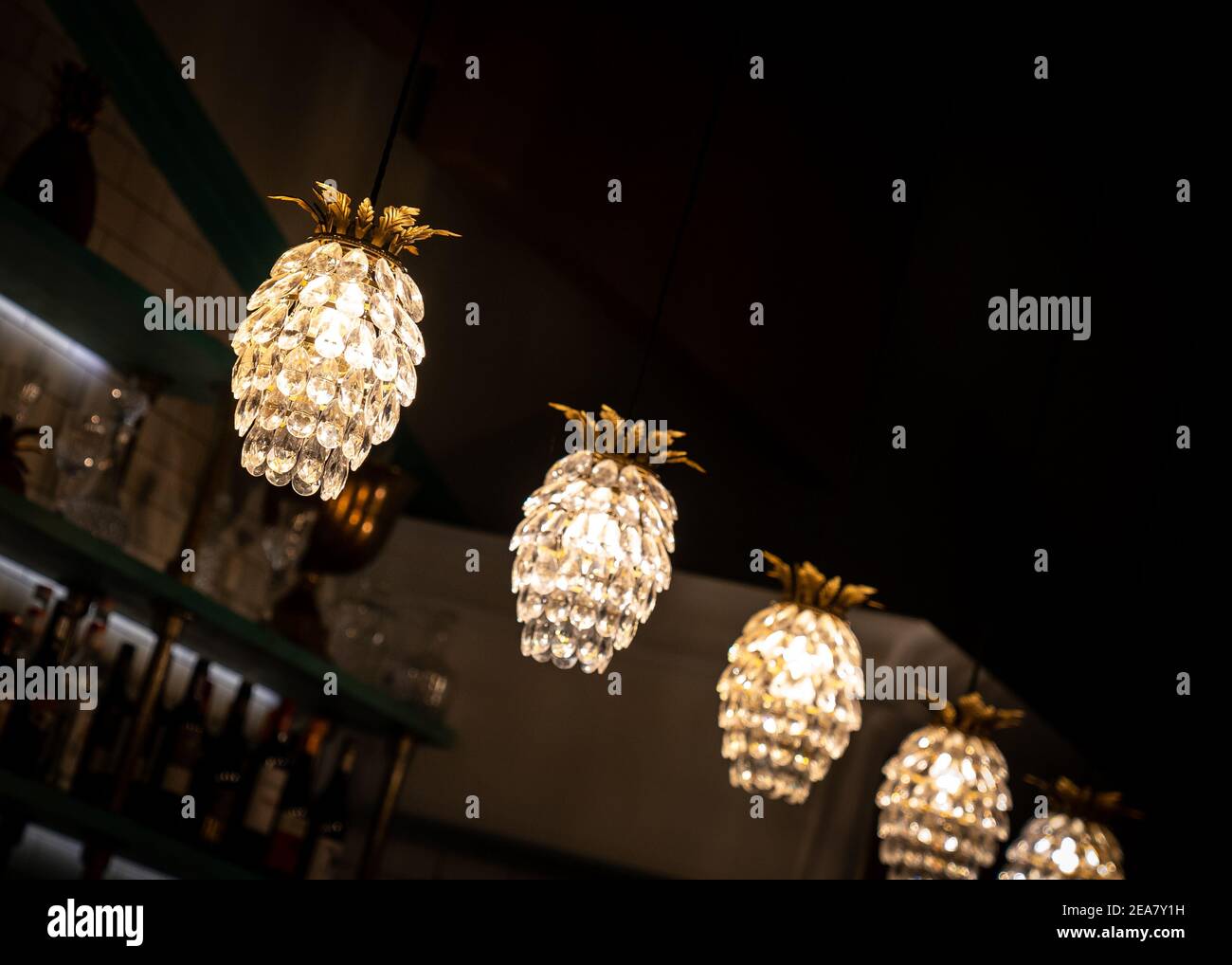 Ananas magnifique Art déco cristal de lumières suspendues au plafond au-dessus du bar éclairé la nuit avec des bouteilles derrière Banque D'Images