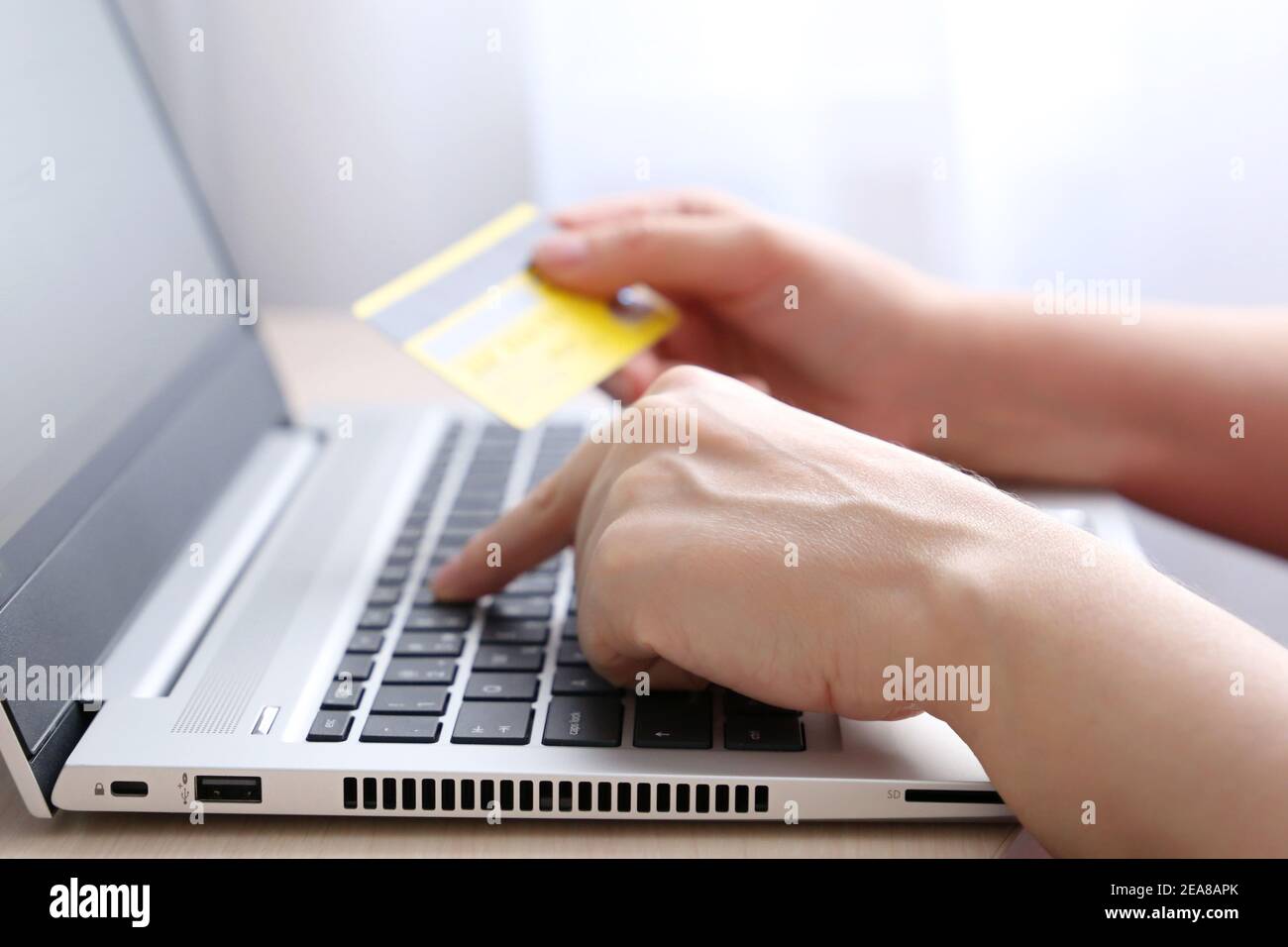 Femme tenant les types de carte de crédit sur le clavier d'ordinateur portable. Concept d'achat et de paiement en ligne, transactions financières Banque D'Images