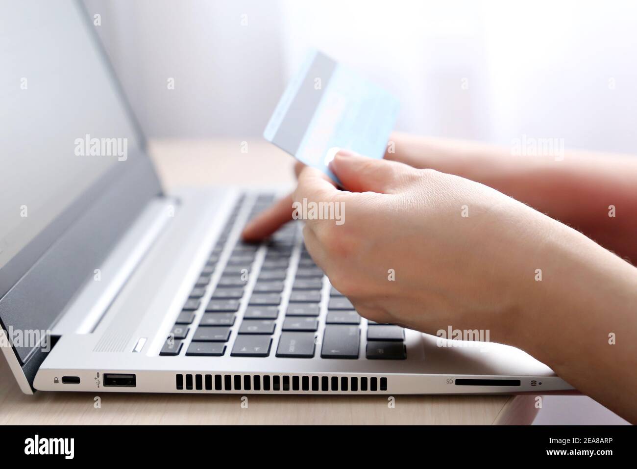 Femme tenant les types de carte de crédit sur le clavier d'ordinateur portable. Concept d'achat et de paiement en ligne, transactions financières Banque D'Images