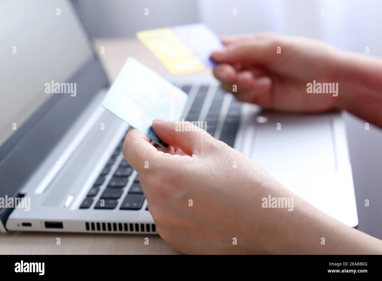 Cartes de crédit dans les mains des femmes sur l'arrière-plan de l'ordinateur portable. Concept d'achat et de paiement en ligne, de remise, de transactions financières Banque D'Images