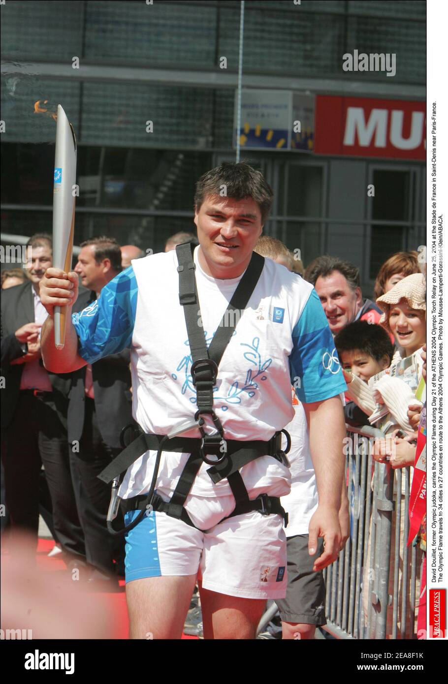 David Douillet, ancien judoka olympique, porte la flamme olympique au cours du jour 21 du Relais de la flamme olympique D'ATHÈNES 2004 le 25 juin 2004 au Stade de France à Saint-Denis près de Paris-France. La flamme olympique se rend dans 34 villes de 27 pays en route vers les Jeux Olympiques d'Athènes en 2004. Photo de Mousse-Lamperti-Gorassini-Klein/ABACA. Banque D'Images