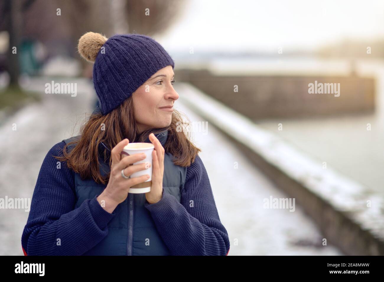 Bonne femme de brunette d'âge moyen qui va pour une promenade et boire un café à emporter Banque D'Images