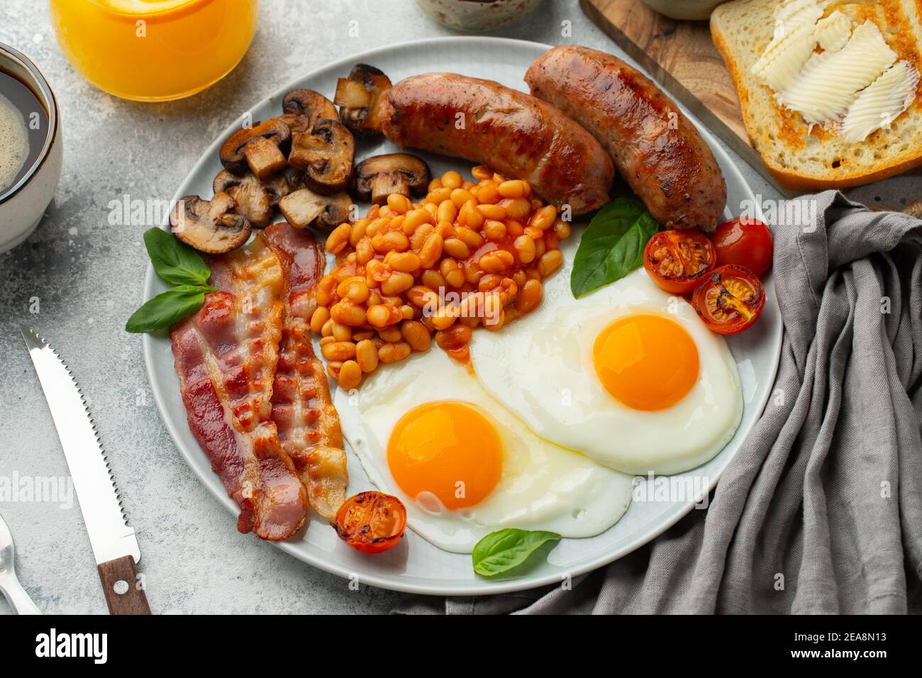 Petit déjeuner anglais complet sur une assiette avec œufs frits, saucisses,  bacon, haricots, toasts et café sur fond de pierre légère. Vue de dessus  Photo Stock - Alamy