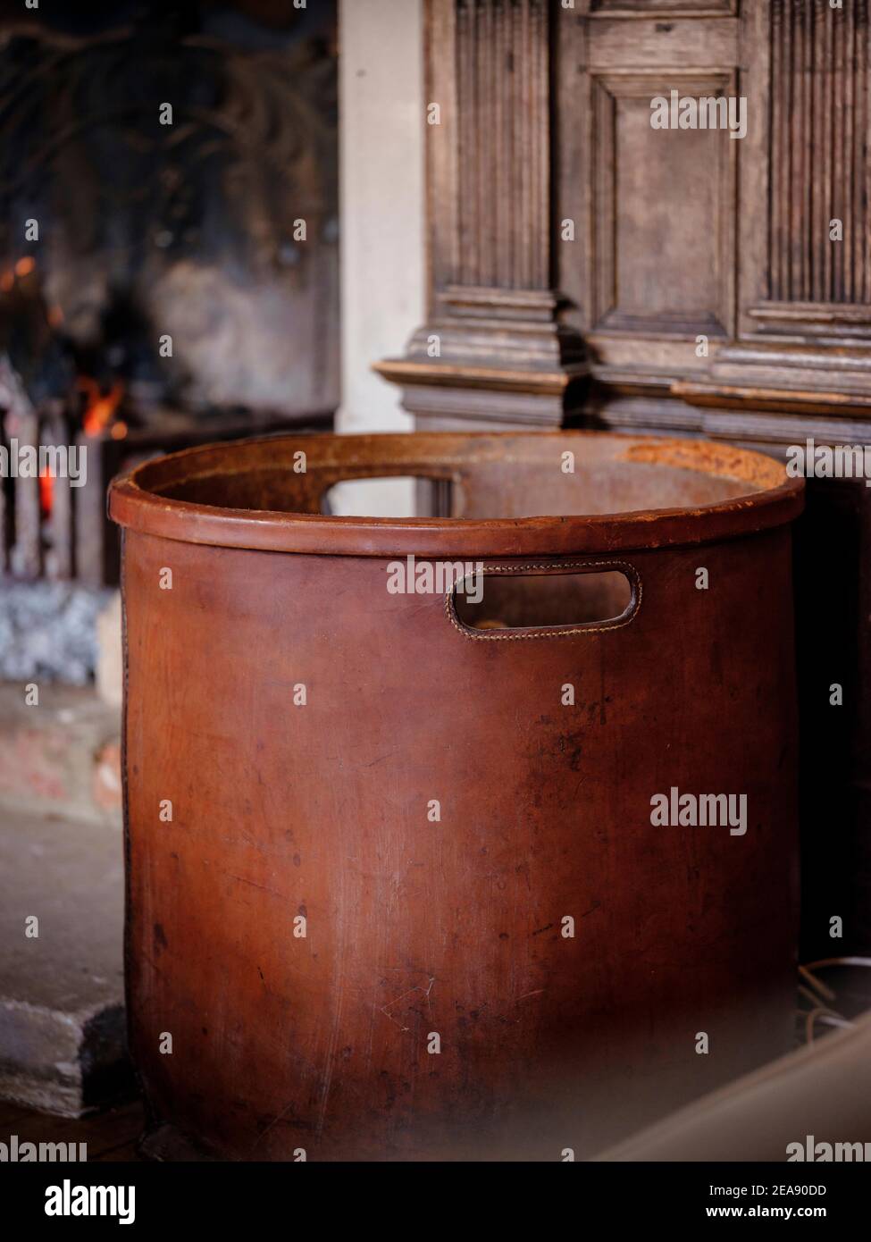 Un panier en bois à côté d'un feu chaud ouvert avec des poutres dans une maison de campagne lambrissée de bois. Banque D'Images