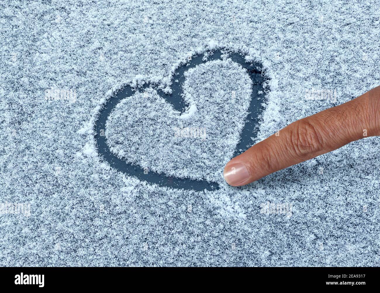 Dessin d'un coeur de neige avec un doigt comme un amusant symbole d'amour d'hiver comme une forme romantique de Valentin salutations sur une surface froide givrée. Banque D'Images