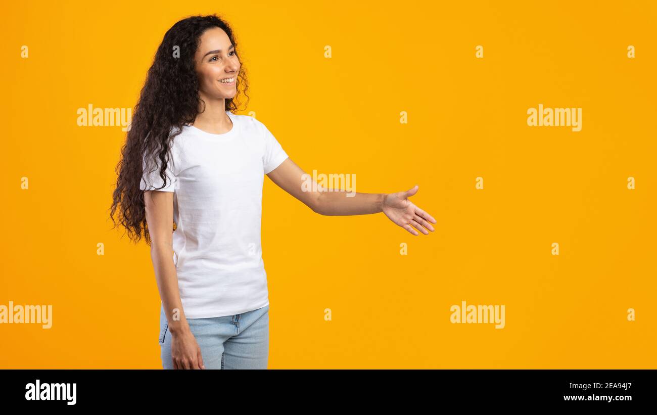 Femme offrant la main pour le message d'accueil Handshake de côté, fond jaune, vue latérale Banque D'Images