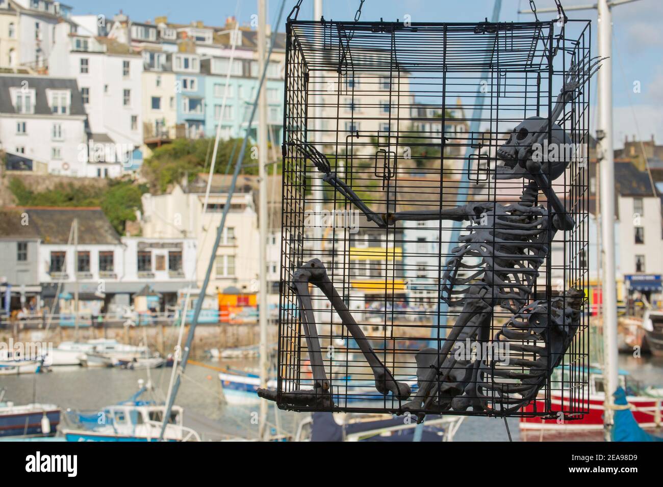 Squelette humain artificiel en cage surplombant le port intérieur de Brixham. Brixham a une grande flotte de pêche, est populaire auprès des touristes et est l'hôte d'un p Banque D'Images