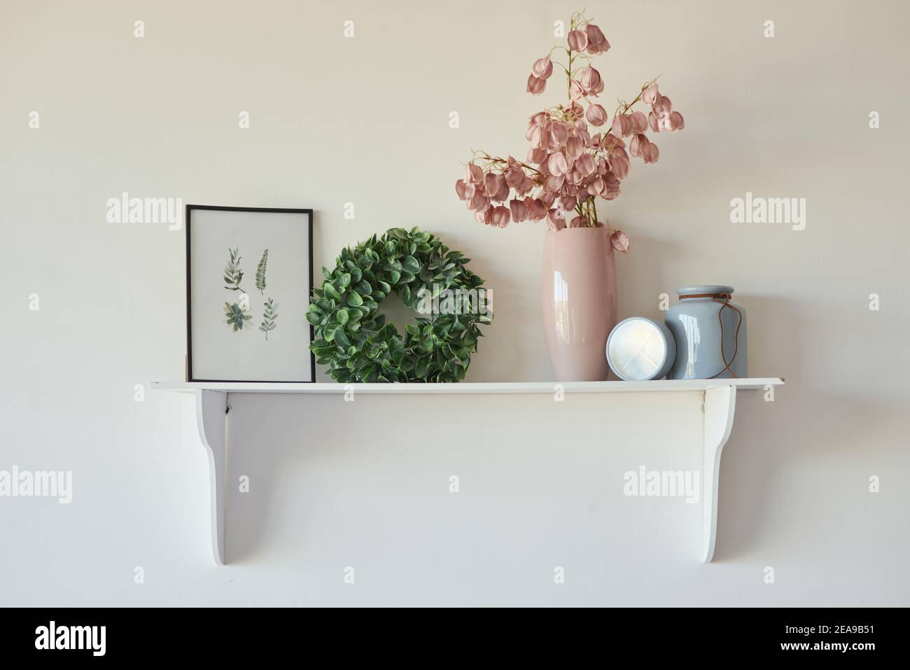 Décorez par vous-même. Étagère décorative sur un mur blanc avec cadre et fleurs dans un vase Banque D'Images