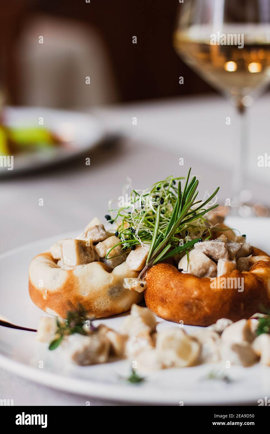 Champignons farcis au fromage, tige de champignons et micro-vert sur la plaque blanche avec un verre de vin au restaurant Banque D'Images