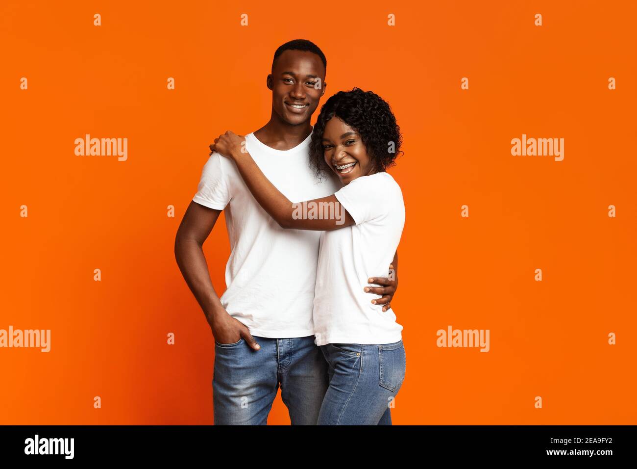 Joyeux couple noir amoureux ensergeant sur l'orange Banque D'Images