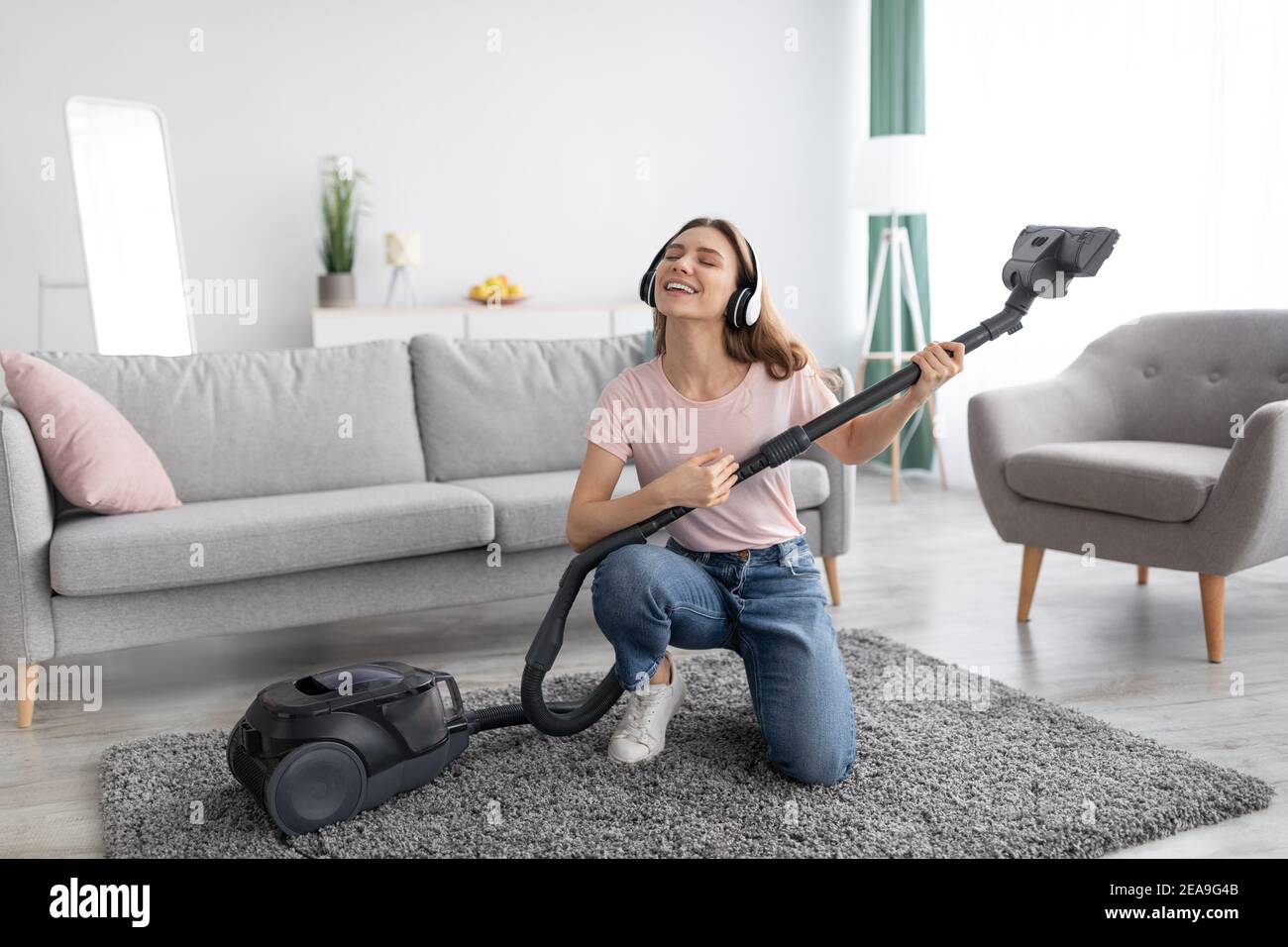 Le nettoyage est amusant. Une jeune femme au foyer écoute de la musique  dans un casque tout en passant l'aspirateur dans son appartement, en  utilisant hoover comme guitare Photo Stock - Alamy