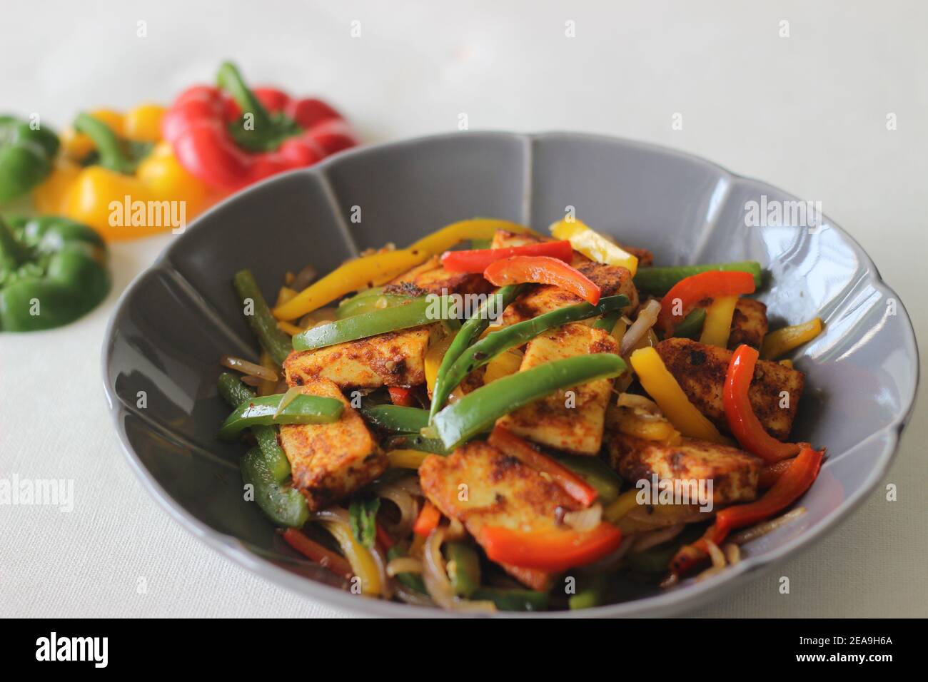 Paneer poêlé Tawa et poivrons sautés. Une combinaison savoureuse comme plat de départ. Photographié dans un bol en forme de fleur sur fond blanc. Banque D'Images