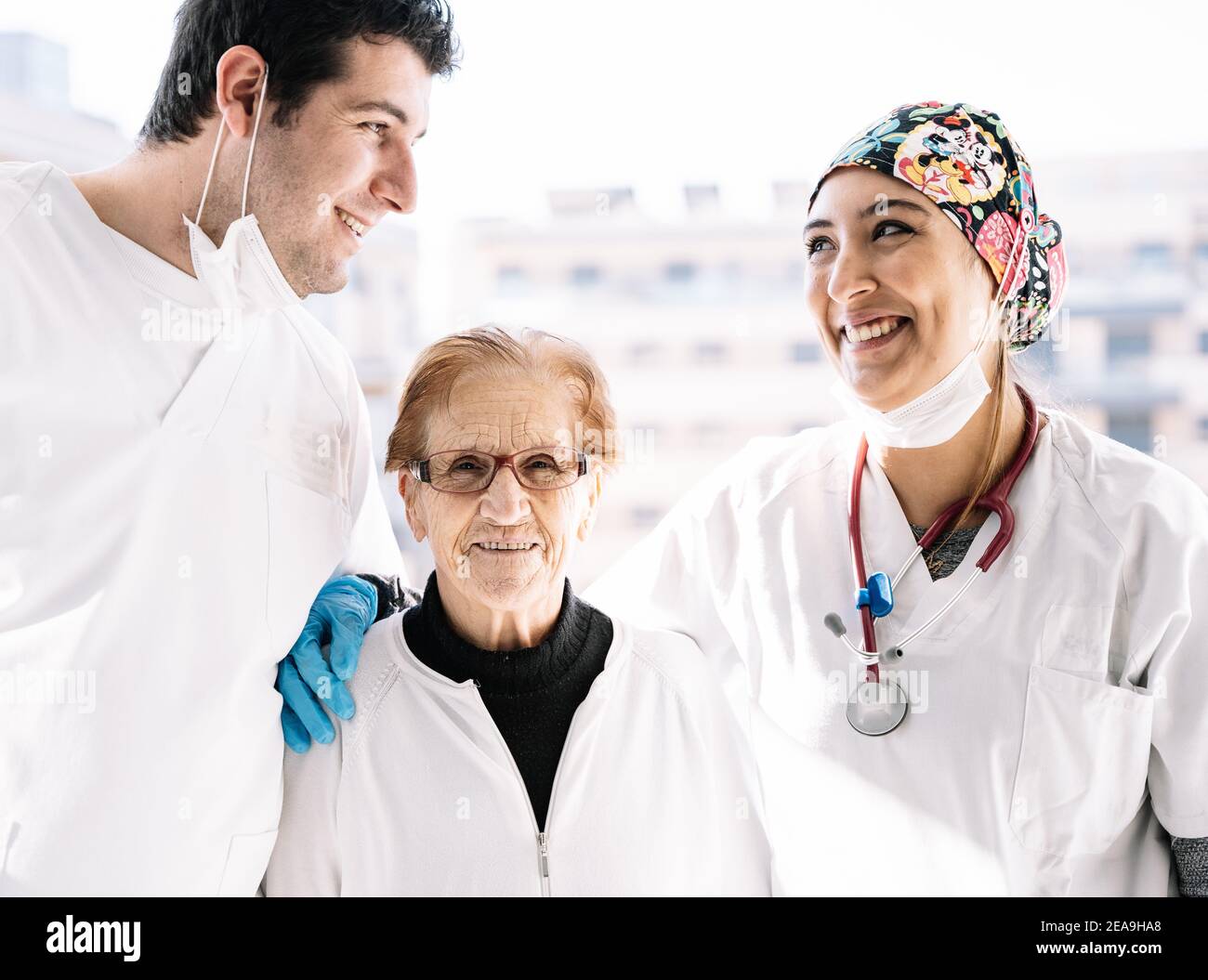 Les médecins se réjouissaient de s'embrasser chez une femme âgée pendant qu'elle était assise dans la chambre avec lumière du soleil et sourire Banque D'Images