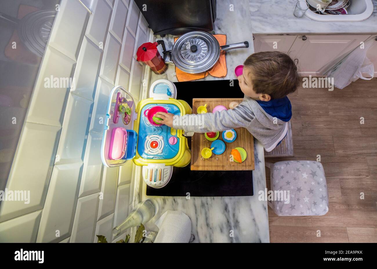 Enfant garçon jouant avec la cuisine jouet sur le vrai comptoir de cuisine.  Prise de vue grand angle en hauteur. Les mouvements sont légèrement flous  Photo Stock - Alamy
