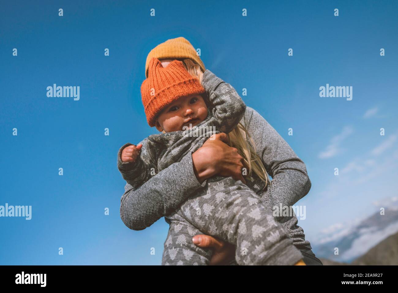 Bébé et mère marchant en plein air voyage famille vacances style de vie enfant mignon portant un chapeau tricoté orange automne saison Banque D'Images