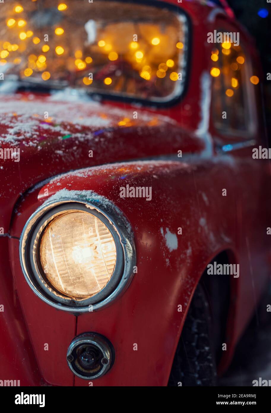 Voiture de rareté rouge enneigée avec éclairage festif du nouvel an. Banque D'Images