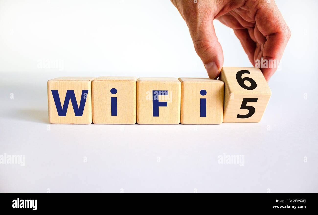 Symbole Wi-Fi 5 ou 6. Homme d'affaires transforme un cube en bois et transforme les mots WiFi 5 en WiFi 6. Magnifique arrière-plan blanc, espace de copie. Affaires, technolo Banque D'Images