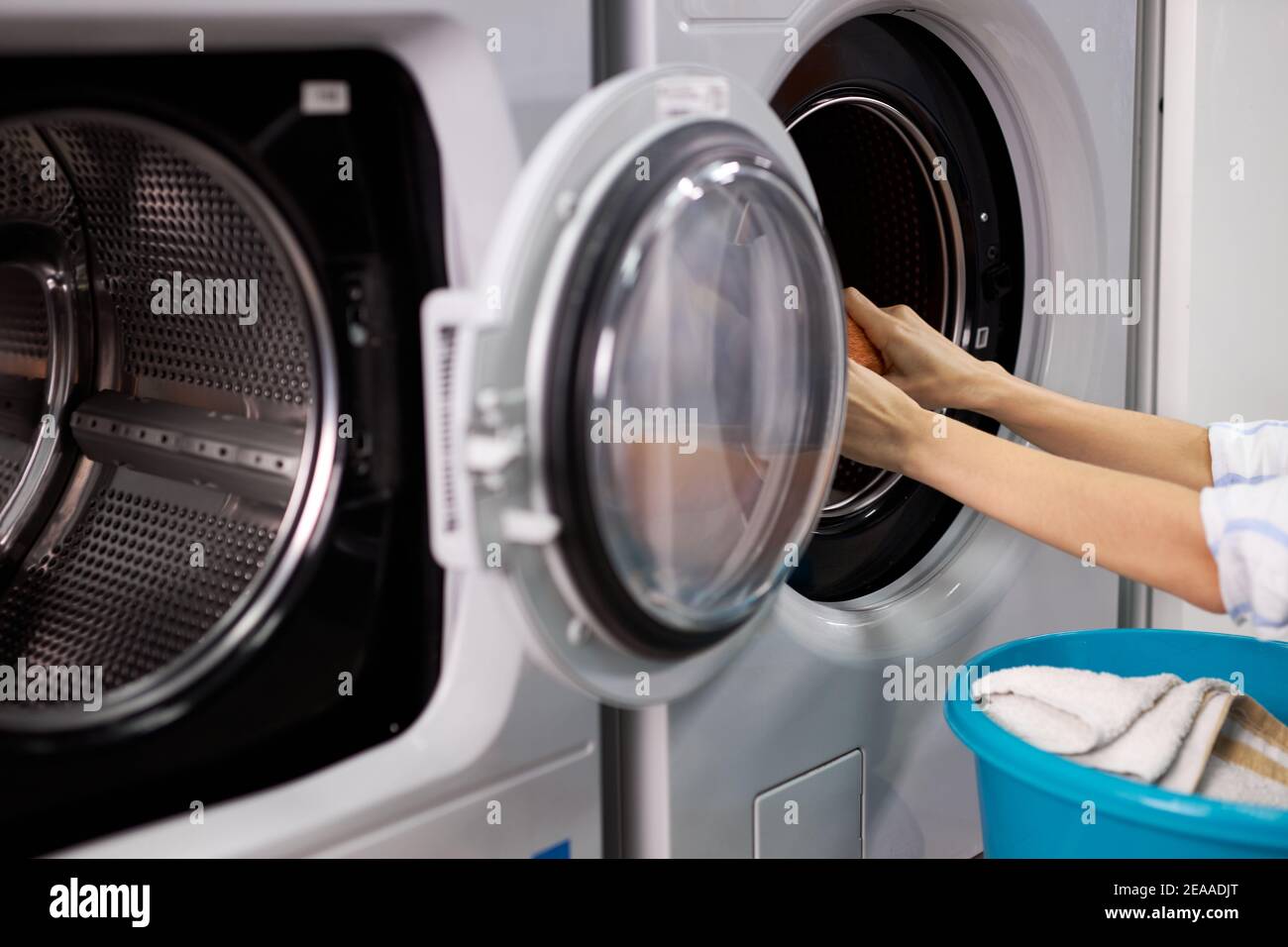 femme méconnaissable dans la maison de lavage triant des vêtements propres, faisant des tâches ménagères, femme sort des vêtements de la machine à laver, tenant lavabo Banque D'Images