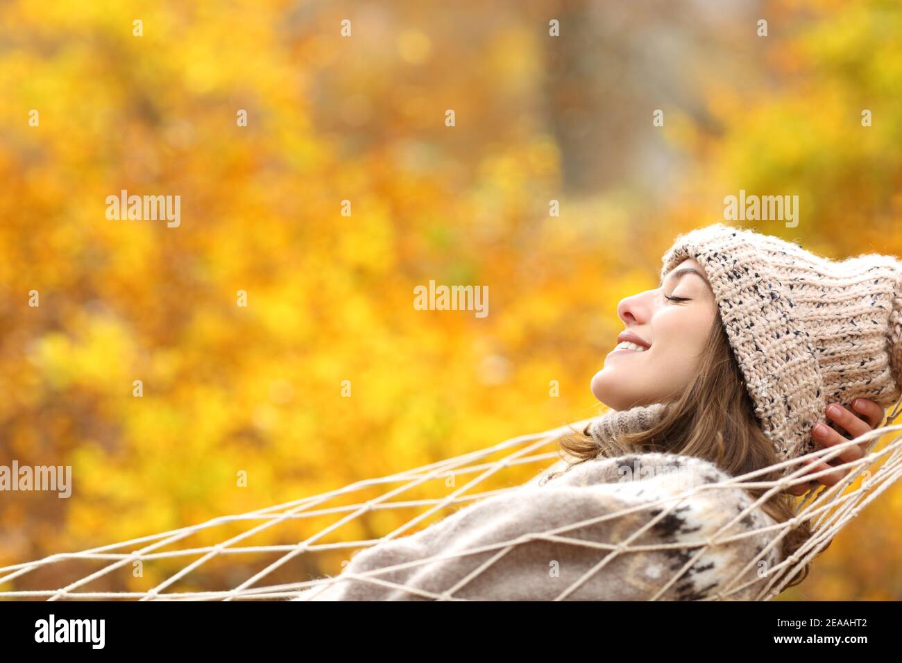 Portrait d'une femme heureuse se reposant sur une vue latérale un hamac en automne dans une forêt Banque D'Images