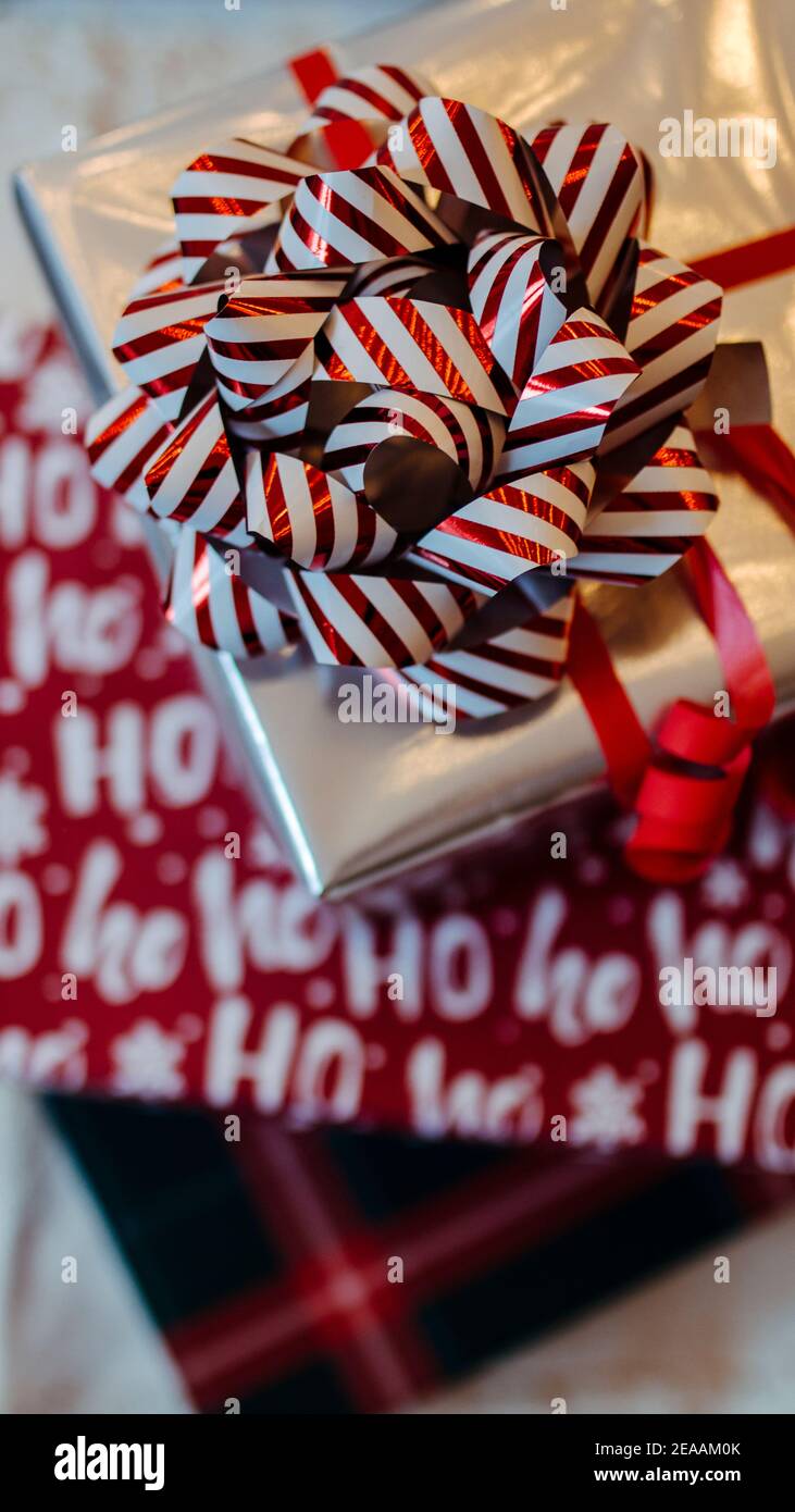 Cadeaux de Noël empilés, papier d'emballage avec inscription Hohoho et grand noeud rouge et blanc, Banque D'Images