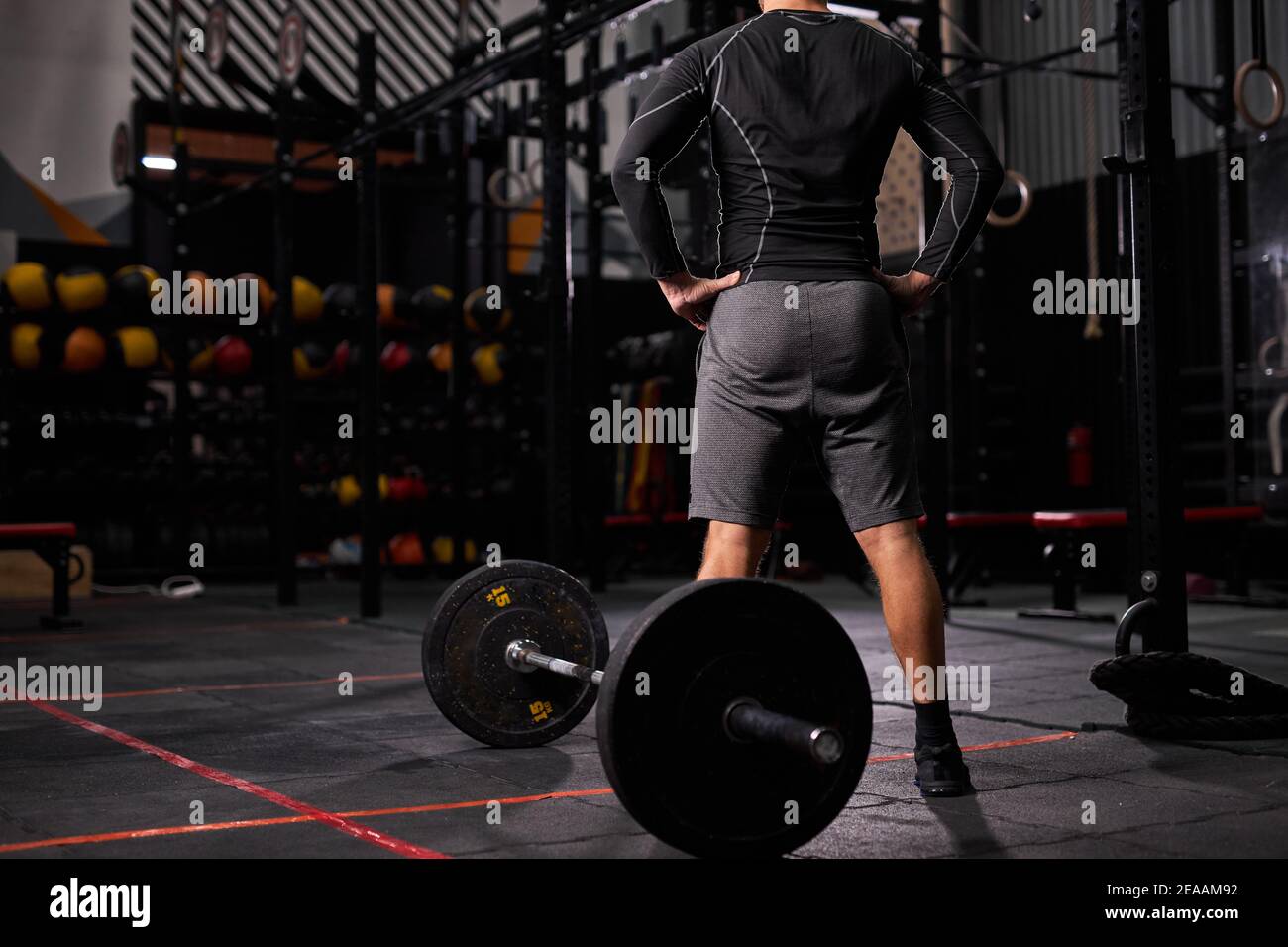 vue arrière sur un sportif se tenant près d'une barbell en pause, repos.  homme en tenue sportive dans une salle de gym moderne Photo Stock - Alamy