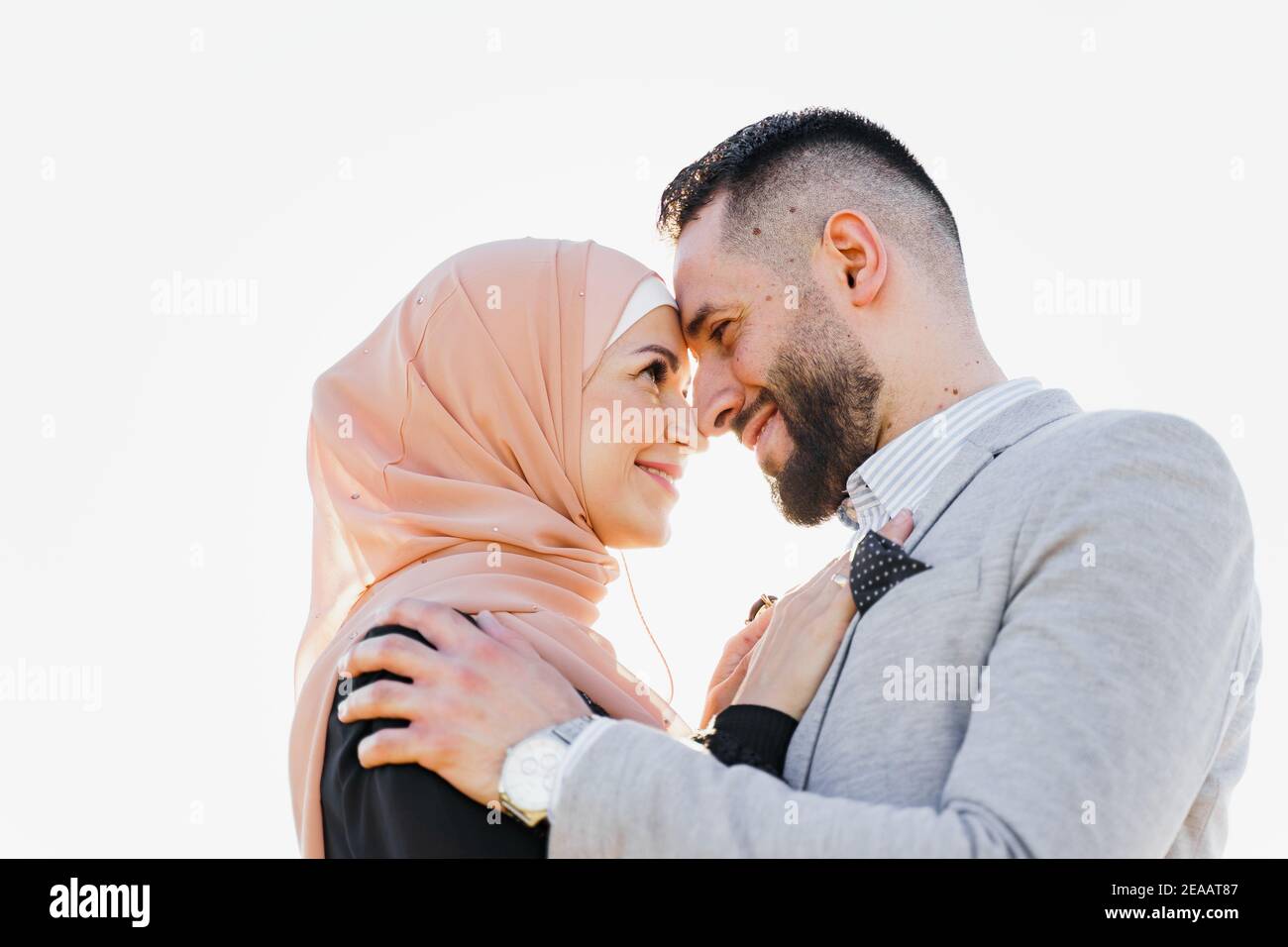Gros plan sur l'histoire de l'amour musulman à la lumière du soleil. Couple  souriant et câlins au coucher du soleil. Une femme qui a pris le hijab  regarde son homme. Publicité pour