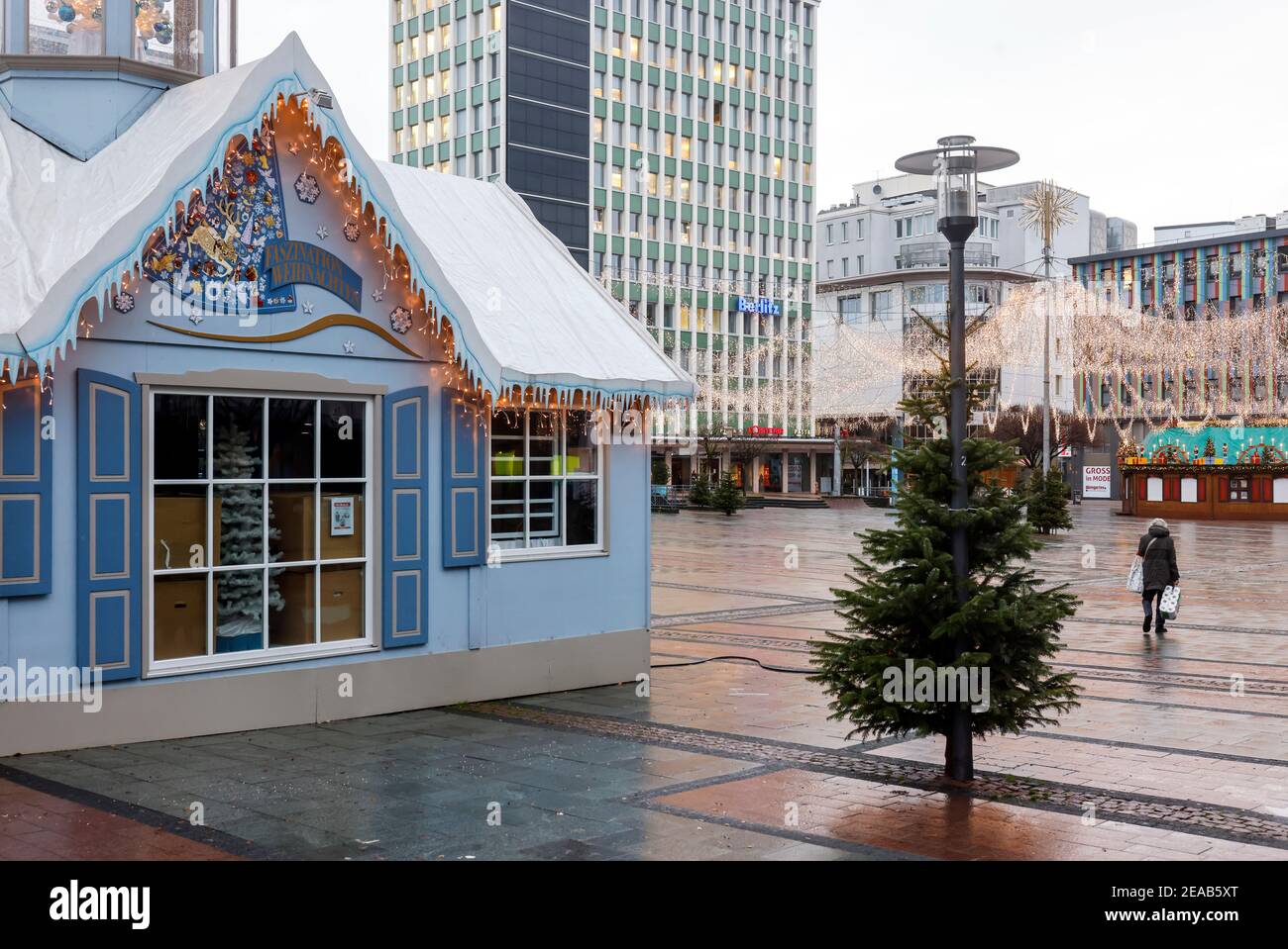 Essen, région de la Ruhr, Rhénanie-du-Nord-Westphalie, Allemagne - Essen centre-ville en temps de crise de la corona avec le deuxième verrouillage le jour avant la veille de Noël, les magasins et les quelques étals du marché de Noël sont fermés, un senior citoyen marche à travers la Kennedyplatz vide avec ses achats. Banque D'Images