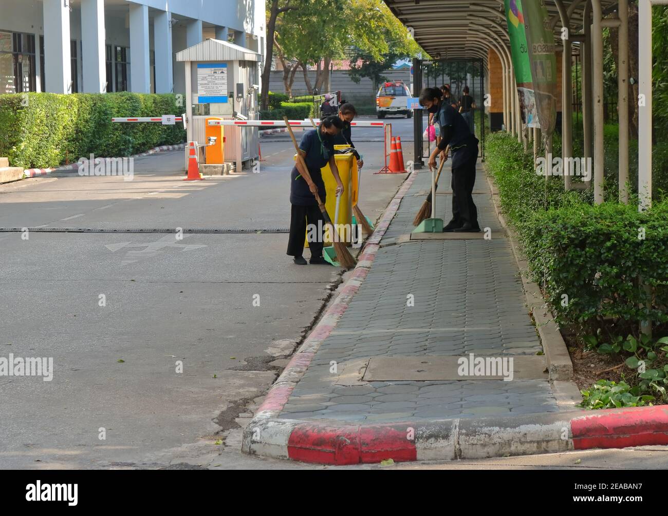 Bangkok, Thaïlande - 2 février 2021 : les travailleuses baladent les rues et les trottoirs en utilisant des balais et des pelles à poussière, les balais sont en mouvement flou Banque D'Images