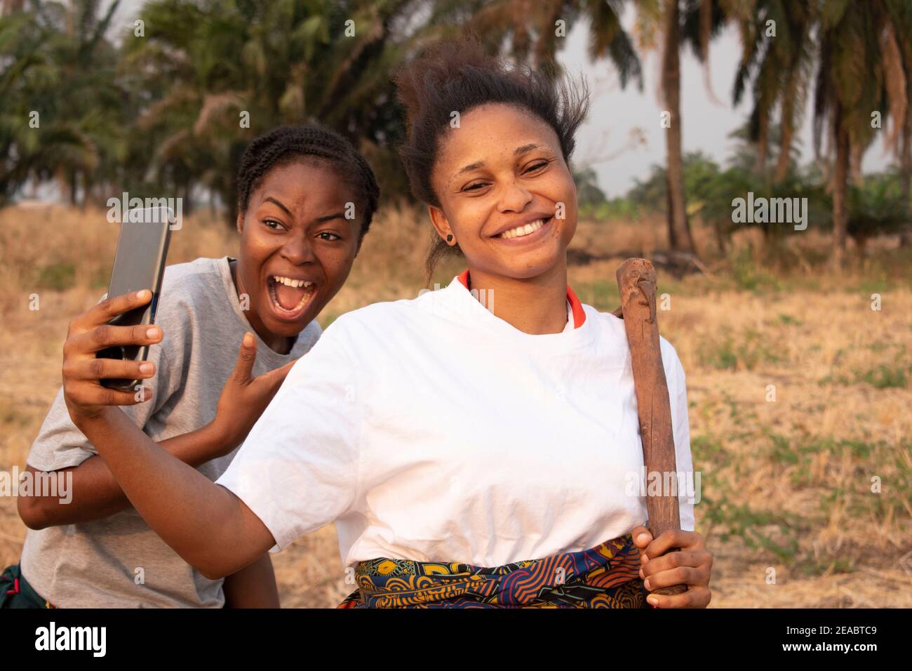 deux femmes utilisant un téléphone portable dans une terre agricole Banque D'Images