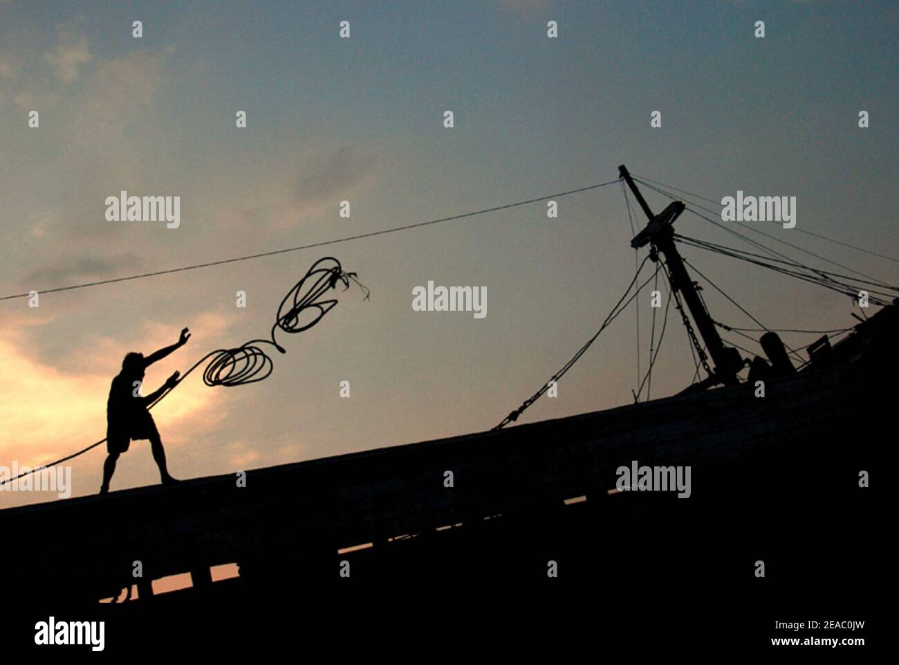 Un équipage de bateau jette une corde à la plate-forme du port, où son collègue attend de lier le navire. Port traditionnel de Sunda Kelapa, Penjaringan, Jakarta, Indonésie. Banque D'Images