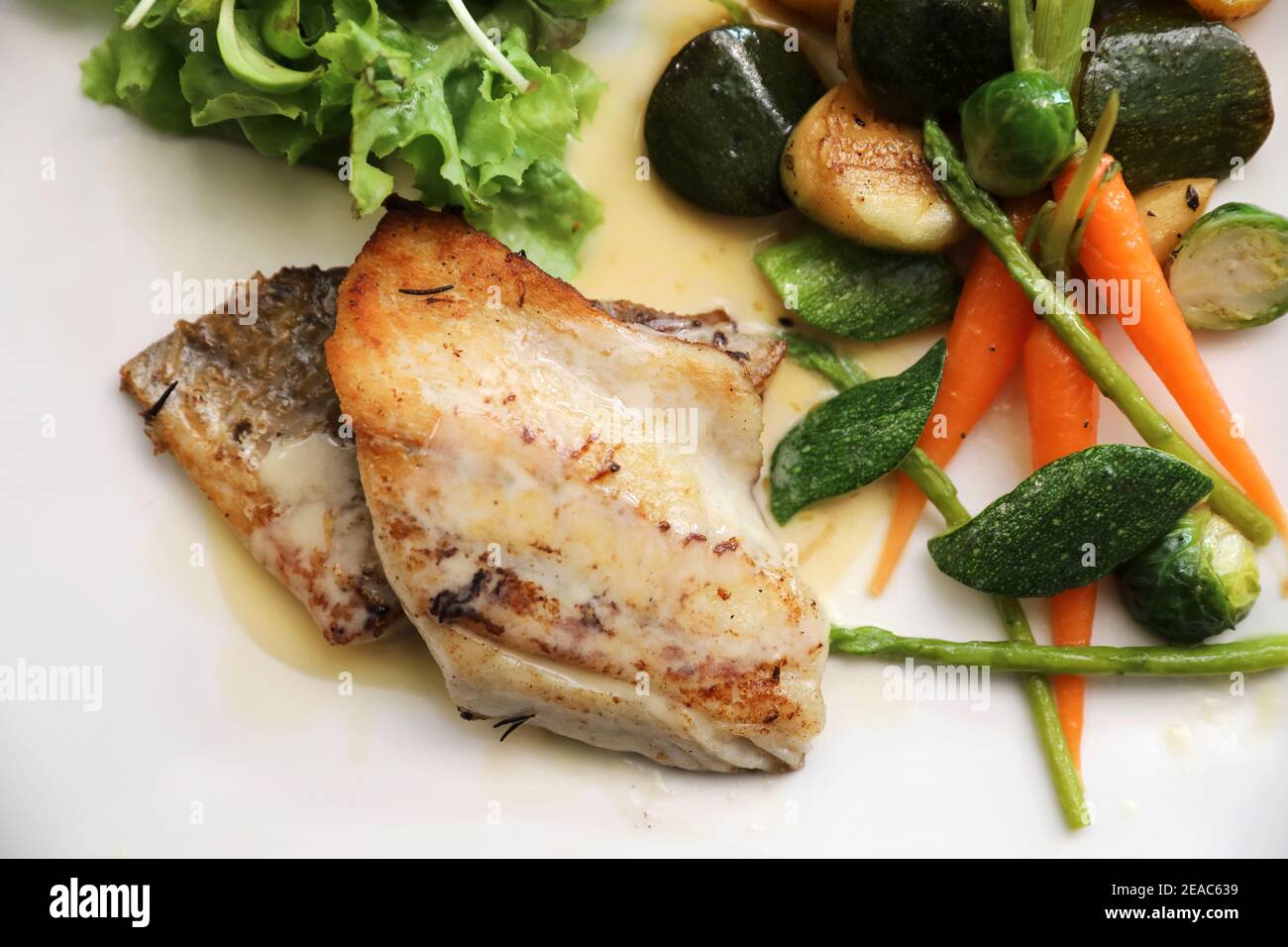 Filet de loup de mer, légumes grillés et salade sur table en bois Banque D'Images