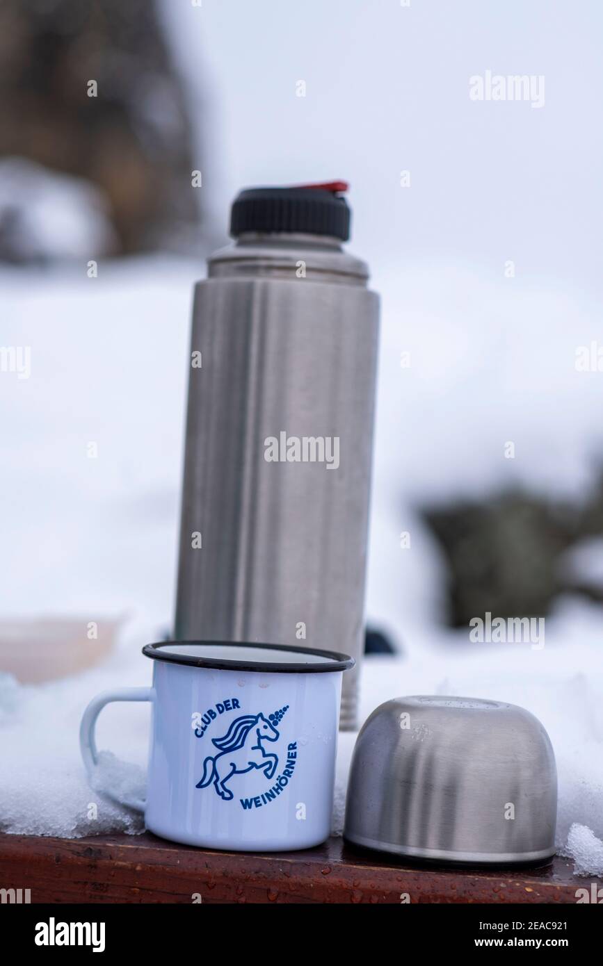 Pique-nique en hiver, un thermos est derrière une tasse en métal avec l'inscription 'Club der Weinhörner'. Banque D'Images