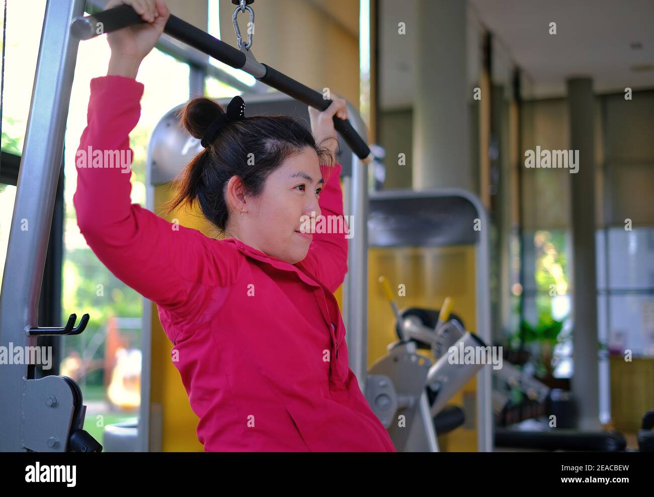 Une femme asiatique attirante est au milieu de son entraînement, haltérophilie en utilisant un latissimus dorsi ou une machine à tirer Lat pour renforcer son Bo supérieur Banque D'Images