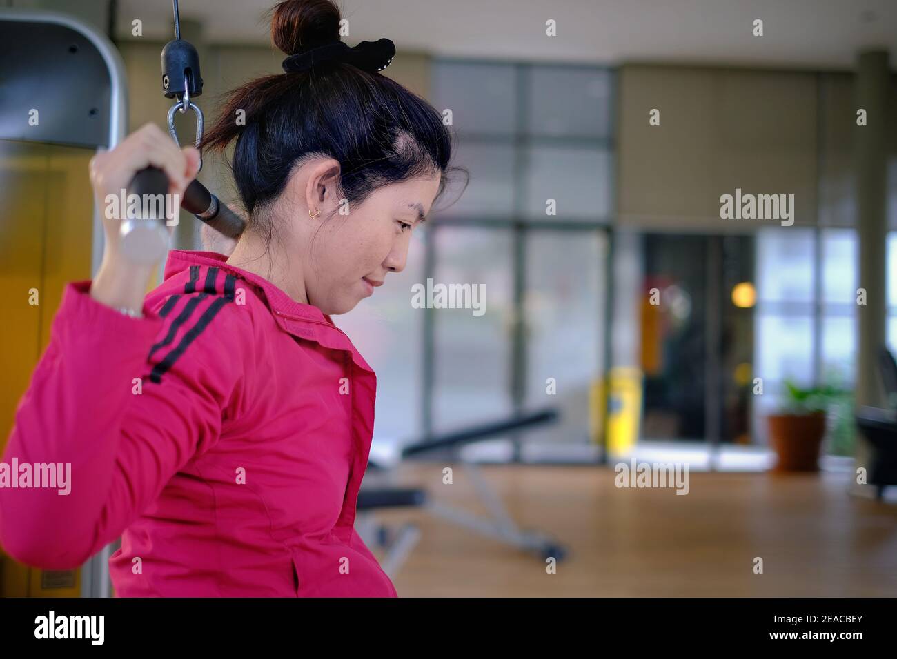 Une femme asiatique attirante est au milieu de son entraînement, haltérophilie en utilisant un latissimus dorsi ou une machine à tirer Lat pour renforcer son Bo supérieur Banque D'Images