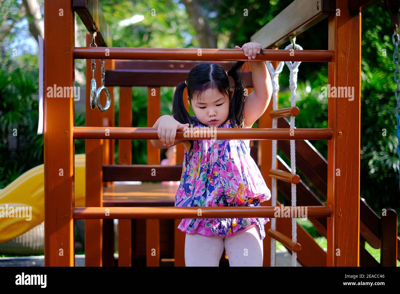 Une jeune fille asiatique mignonne joue à un terrain de jeu, essayant de grimper une échelle en s'amusant et se sentant heureux. Banque D'Images