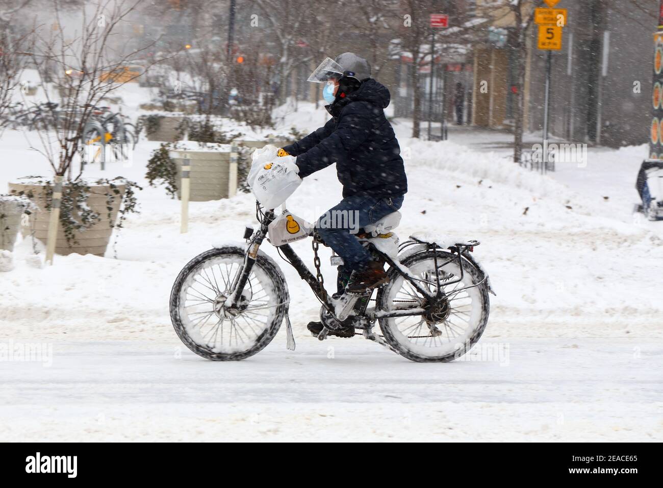 Un préposé à la livraison de nourriture qui fait du vélo électrique par temps enneigé. New York, New York Banque D'Images